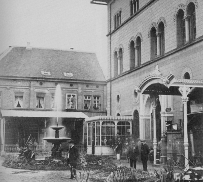 Der östliche Eingang der Fruchthalle ist gut an der Fassade zu erkennen. Ein Springbrunnen und Blumenbeet wirken sehr einladend.
