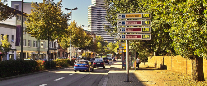 Man blickt die Rudolf-Breitscheid-Straße hinunter in Richtung Rathaus. Mehrere Autos und ein Bus fahren auf dieser Straße über eine grüne Ampel. Direkt vor dem Betrachter steht eine Bushaltestelle. © Stadt Kaiserslautern
