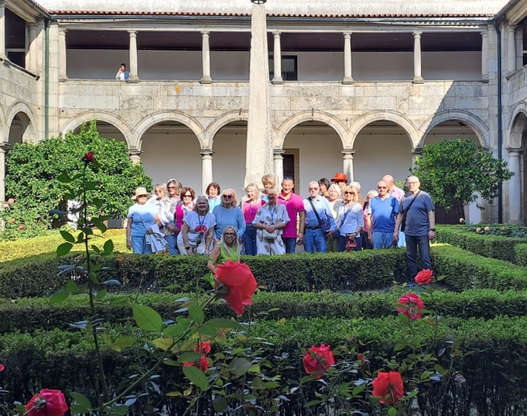 Die Gruppe aus Kaiserslautern mit der Städtepartnerschaftsbeauftragten von Guimaraes (vorne knieend) steht in einem begrünten Innenhof. © Förderkreis KVHS