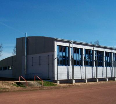 graues Schulgebäude mit blauen Fensterrahmen im Sonnenlicht