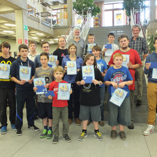 Gruppenbild mit den Preisträgern. Sie stehen auf der Treppe in der Bibliothek und halten ihre Urkunde in der Hand.
