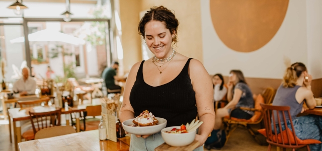 Eine Mitarbeiterin im Café Selen serviert zwei Frühstücksbowls.